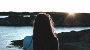 a person sitting on a rock near the water