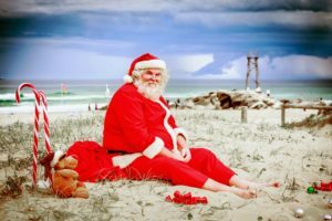 a person in a santa costume sitting on the beach