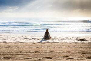 a person sitting on a surfboard on a beach